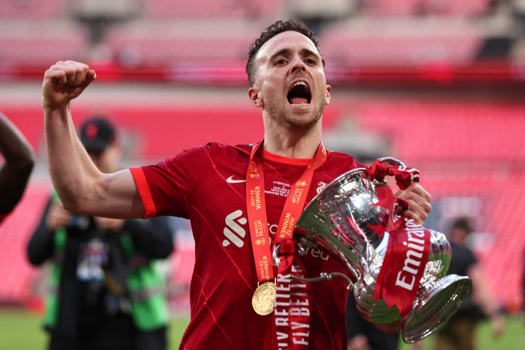 Diogo Jota clenches his fist in celebration as he holds the FA Cup in front of Liverpool supporters at Wembley Stadium.