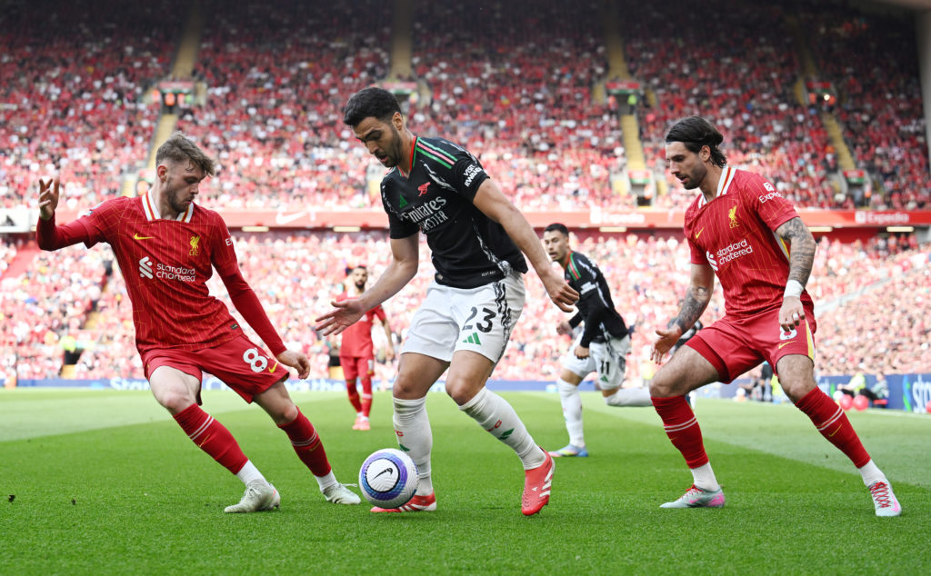 Mikel Merino of Arsenal is challenged by Conor Bradley and Dominik Szoboszlai of Liverpool during the Premier League match between Liverpool FC and Arsenal FC at Anfield