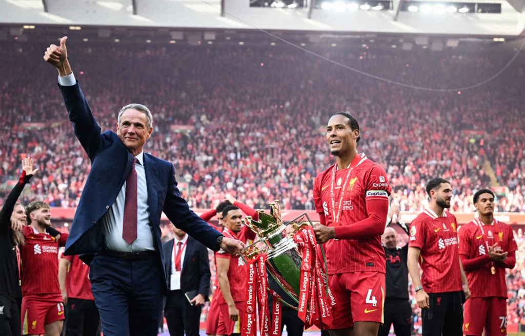 Virgil van Dijk and Alan Hansen hold the Premier League trophy in front of the Kop at Anfield.