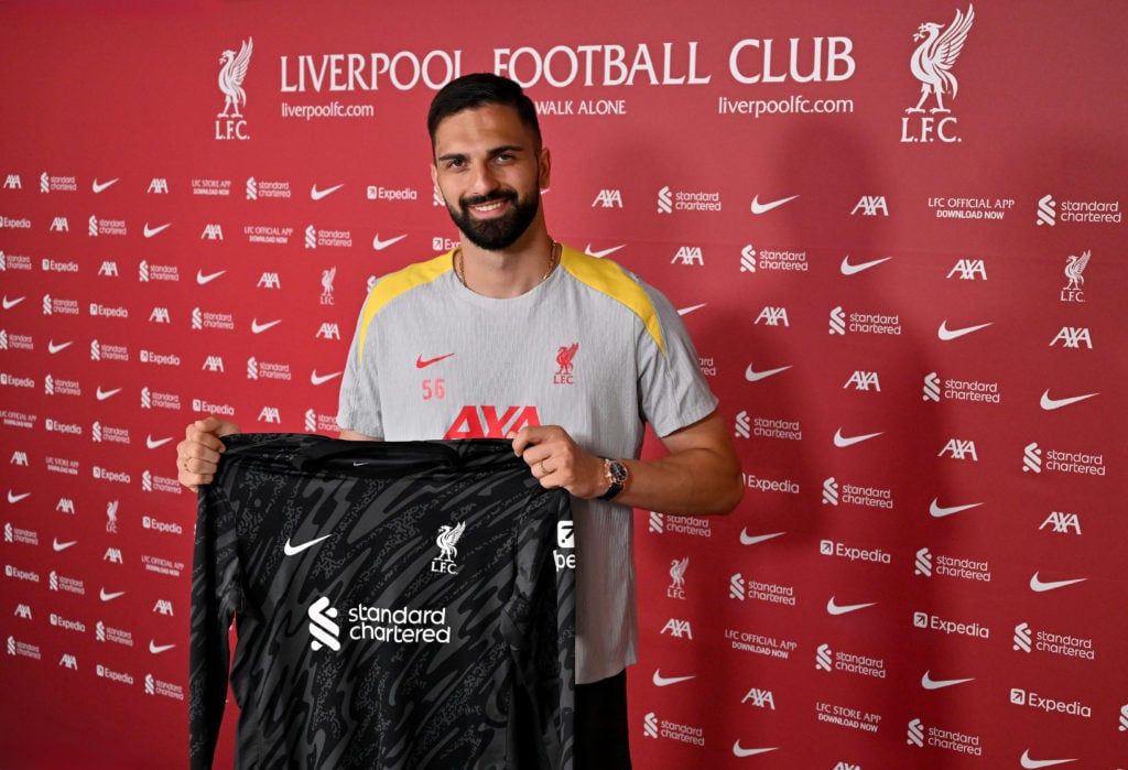 Giorgi Mamardashvili poses with a Liverpool shirt after conducting his first interview with the club at the AXA Training Centre.