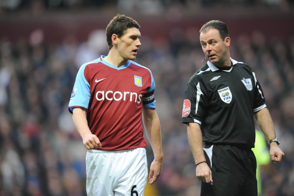 Gareth Barry of Aston Villa and Rob Styles the referee interact on the pitch
