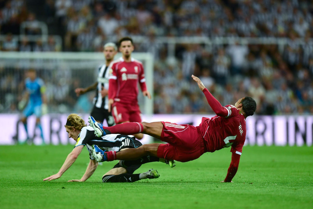 Anthony Gordon fouls Virgil van Dijk before receiving a red card for Newcastle United against Liverpool in the Premier League.