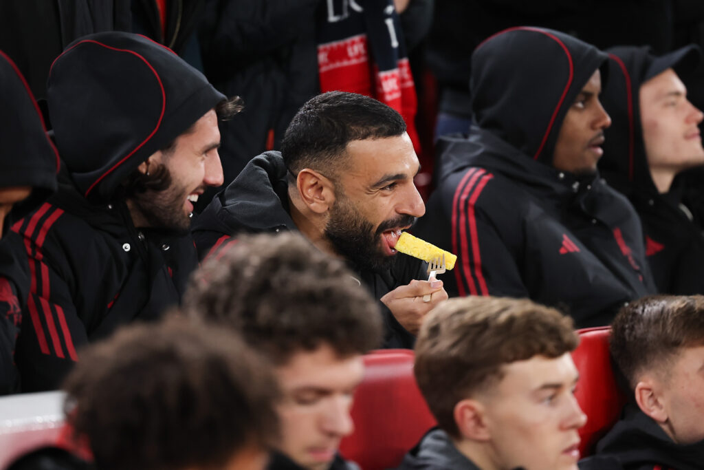 Mohamed Salah of Liverpool eats a chip as he sits on the substitutes bench before the Carabao Cup Fourth Round match between Liverpool and Crystal Palace at Anfield