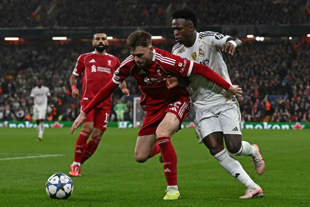 Liverpool's Northern Irish defender #12 Conor Bradley (C) vies with Real Madrid's Brazilian forward #07 Vinicius Junior (R) during the UEFA Champions League, league phase football match between Liverpool and Real Madrid at Anfield