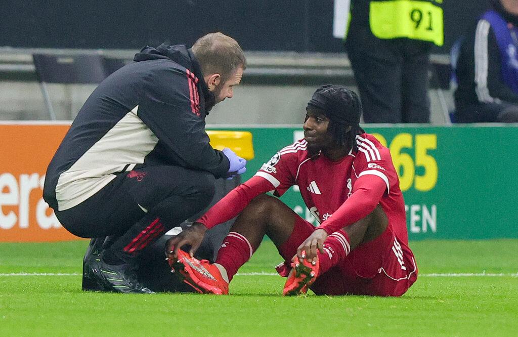 Jeremie Frimpong sits injured on the turf during Liverpool's UEFA Champions League match against Eintracht Frankfurt at Deutsche Bank Park.
