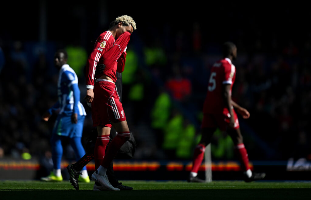 Hugo Ekitike covers his face with his shirt as he comes off injured during Liverpool's Premier League match against Brighton & Hove Albion at the Amex Stadium