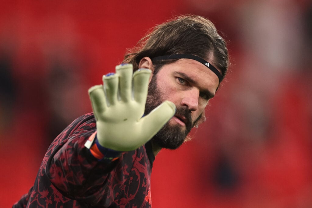 Alisson Becker holds his hand towards the camera while warming up ahead of Liverpool's UEFA Champions League match against Galatasaray